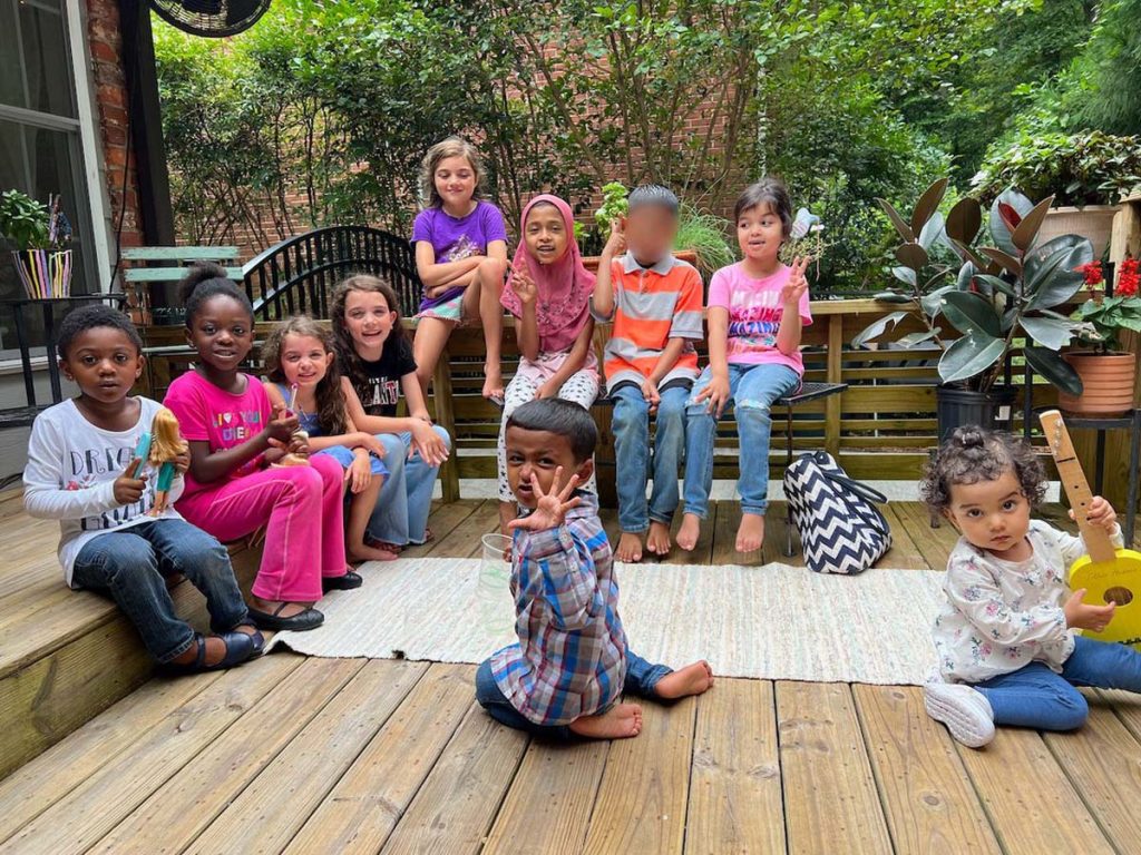 A group of children sit on a wooden deck.