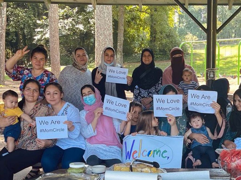 A group of women hold up signs reading, "We Love Mom Circle".