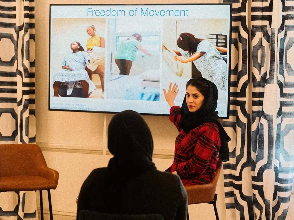 A woman gestures to a slide at a Healthy Moms class.