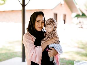 A mother holding her child at an outdoor pavilion.