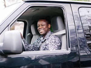 A Friends of Refugees' staff member driving a black vehicle.