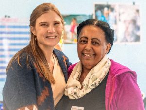 Two women pose for the camera in a classroom.