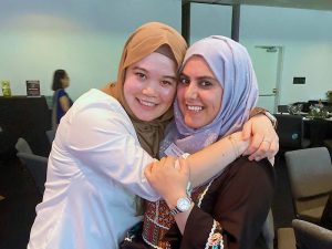 Two women hug while posing for a photo.