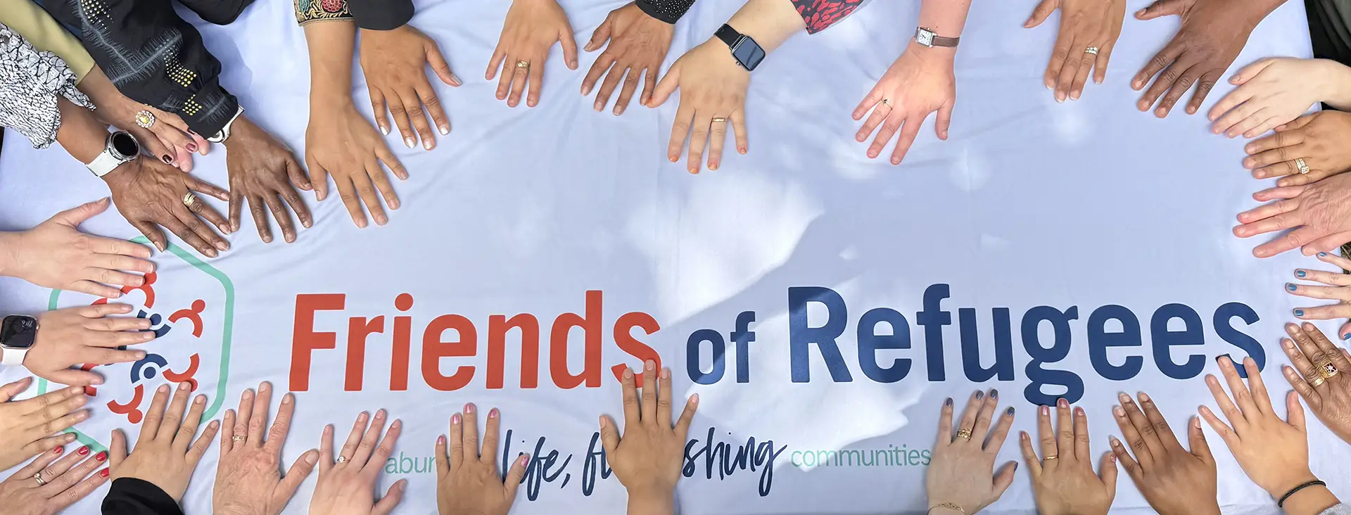 A circle of hands touching a banner with the Friends of Refugee's logo.