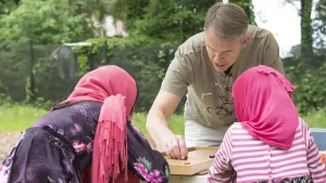 A volunteer plays a table game with two girls at Friends of Refugee's Springfest.