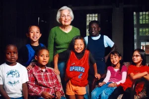 Pat Maddox, founder of Friends of Refugees, posing for a photo with a group of children.
