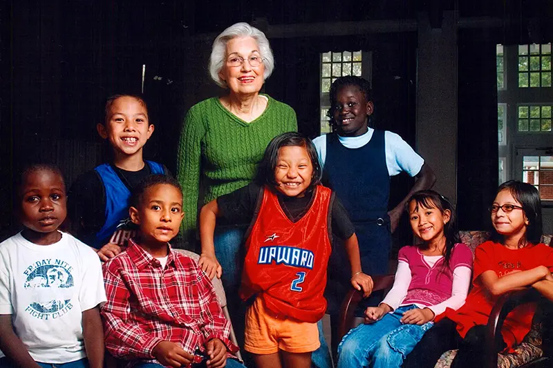 Pat maddox, the founder of Friends of Refugees, poses for a photo, surrounded by refugee children.