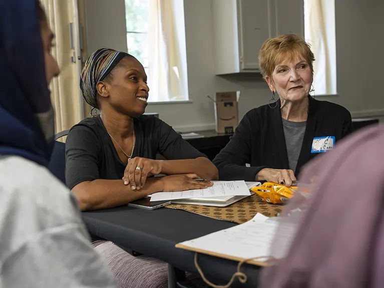 A group of students and a volunteer sit at a table during a Family Job class.