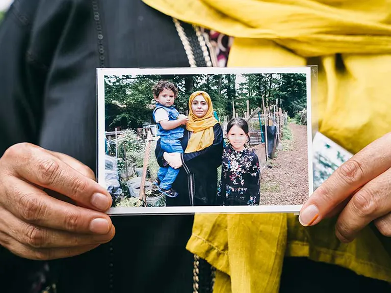 A refugee mother holds a photo of herself with her two young childern.