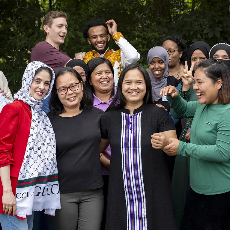 A group of laughing and smiling Friends of Refugees staff members pose for a photo.