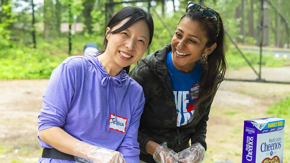 Two volunteers pose for a photo at an outdoor event.