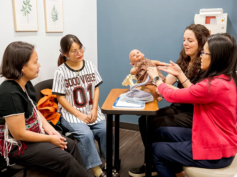 Esther E. Kim, MD, and Virginia Tester, Director of Embrace Refugee Birth Support, consult with an expecting refugee mother.
