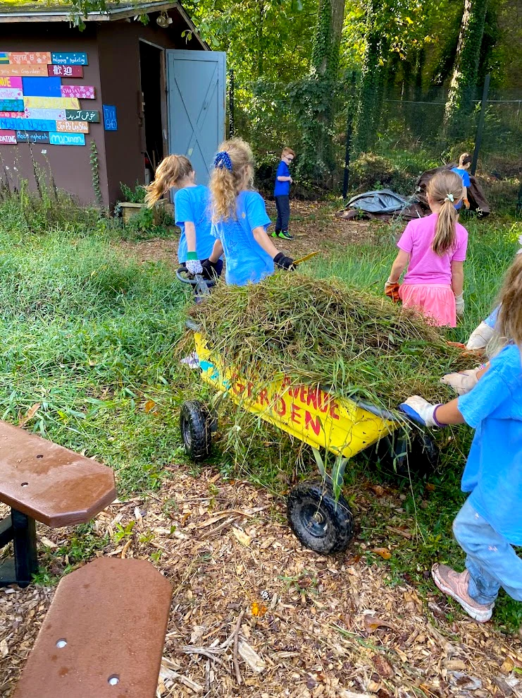 A group of girls pull a waon toward a shed at the Jolly Avenue Garden in Clarkston, GA.